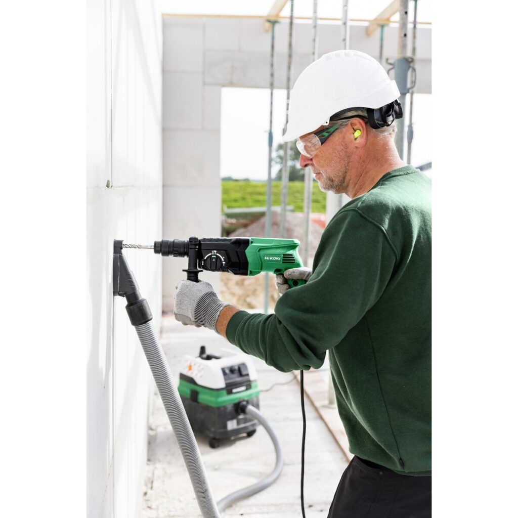 Profesional perforando pared con martillo SDS Plus HiKOKI y sistema de extracción de polvo
